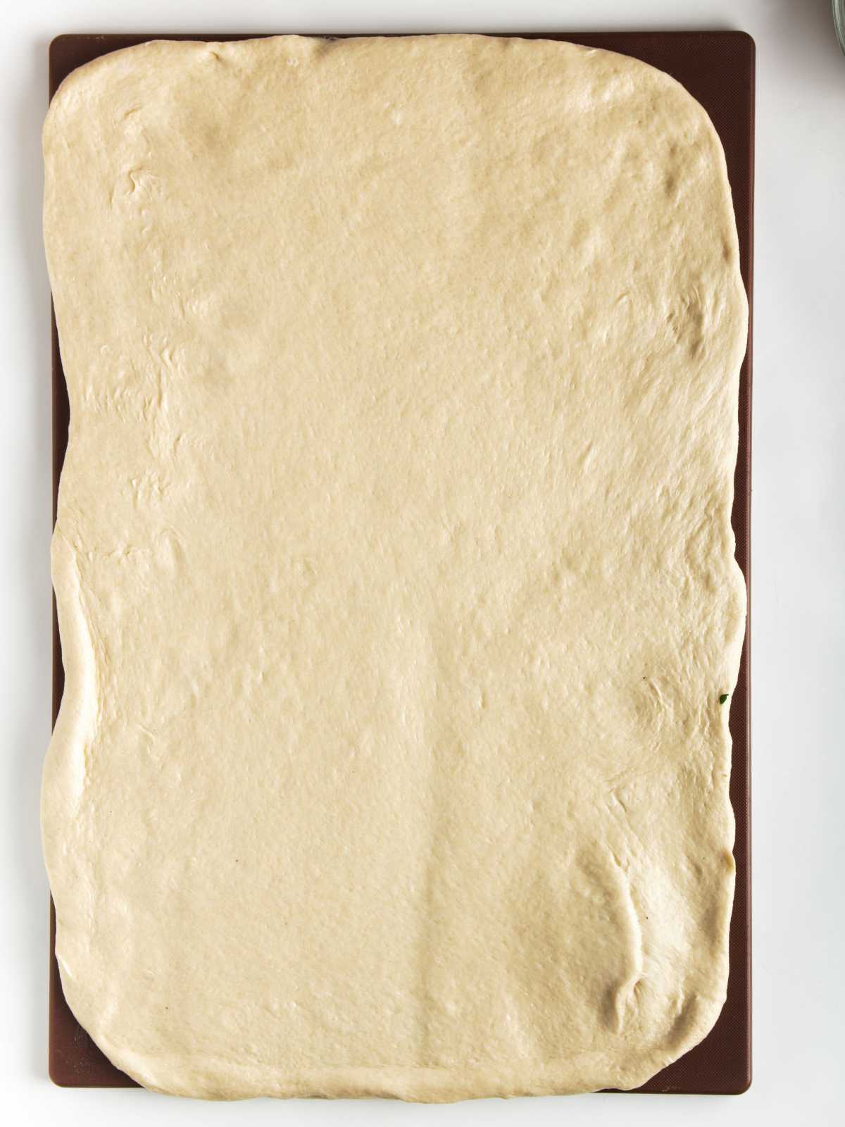 risen sweet bread dough rolled out into a large rectangle shape.