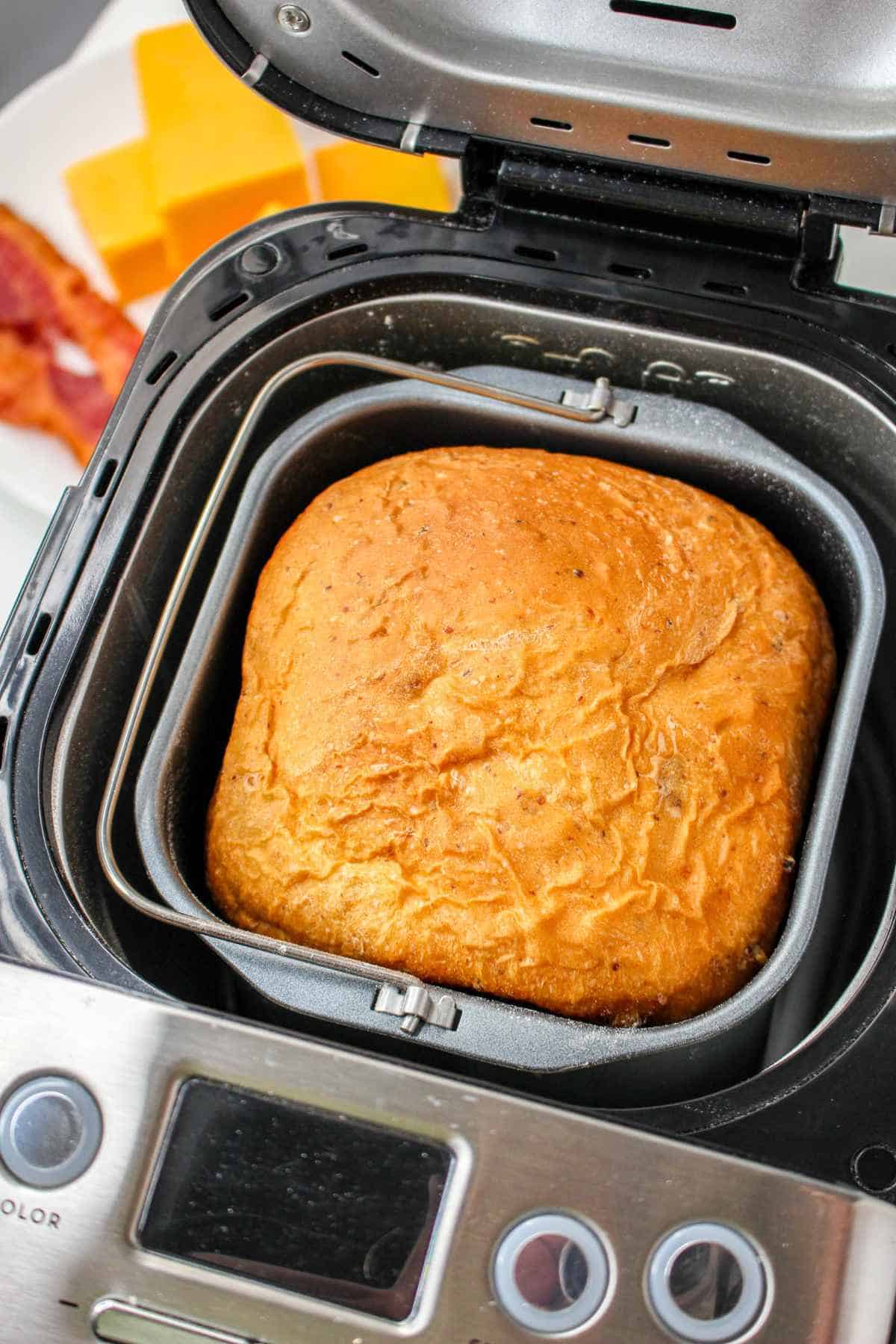 looking down into a bread machine with a loaf of fresh baked bread inside.