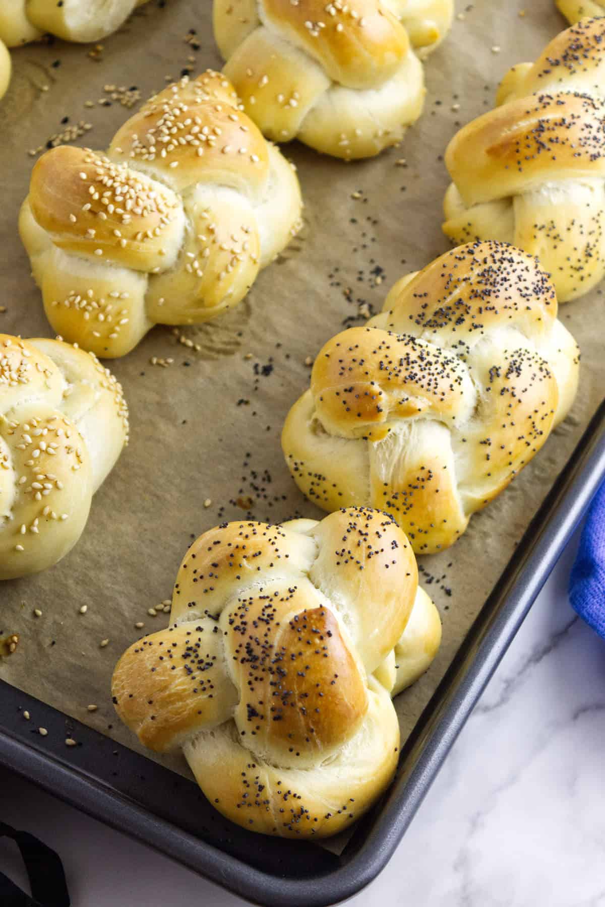 golden brown challah rolls on a baking sheet.