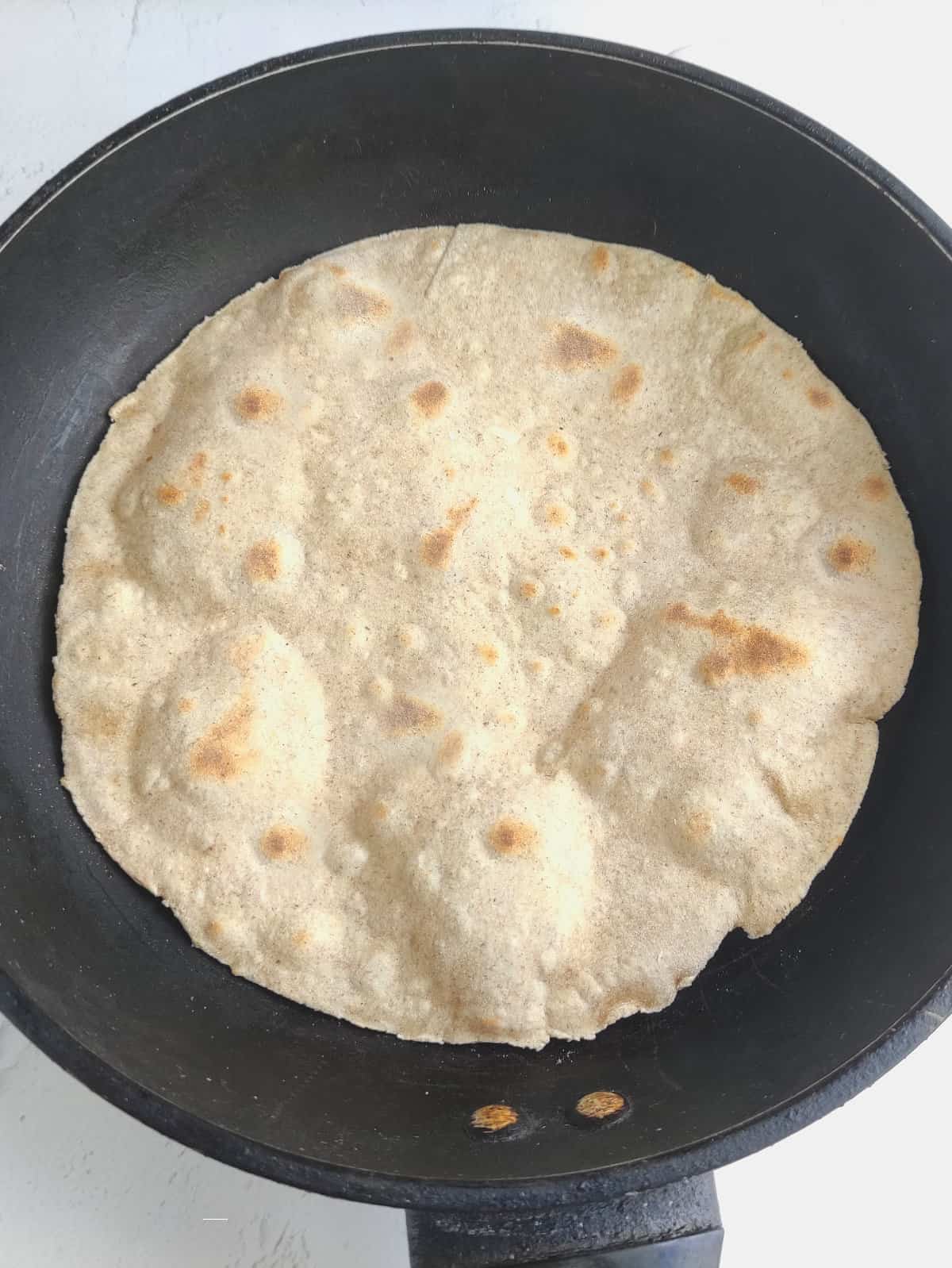 homemade flour tortilla in a skillet.