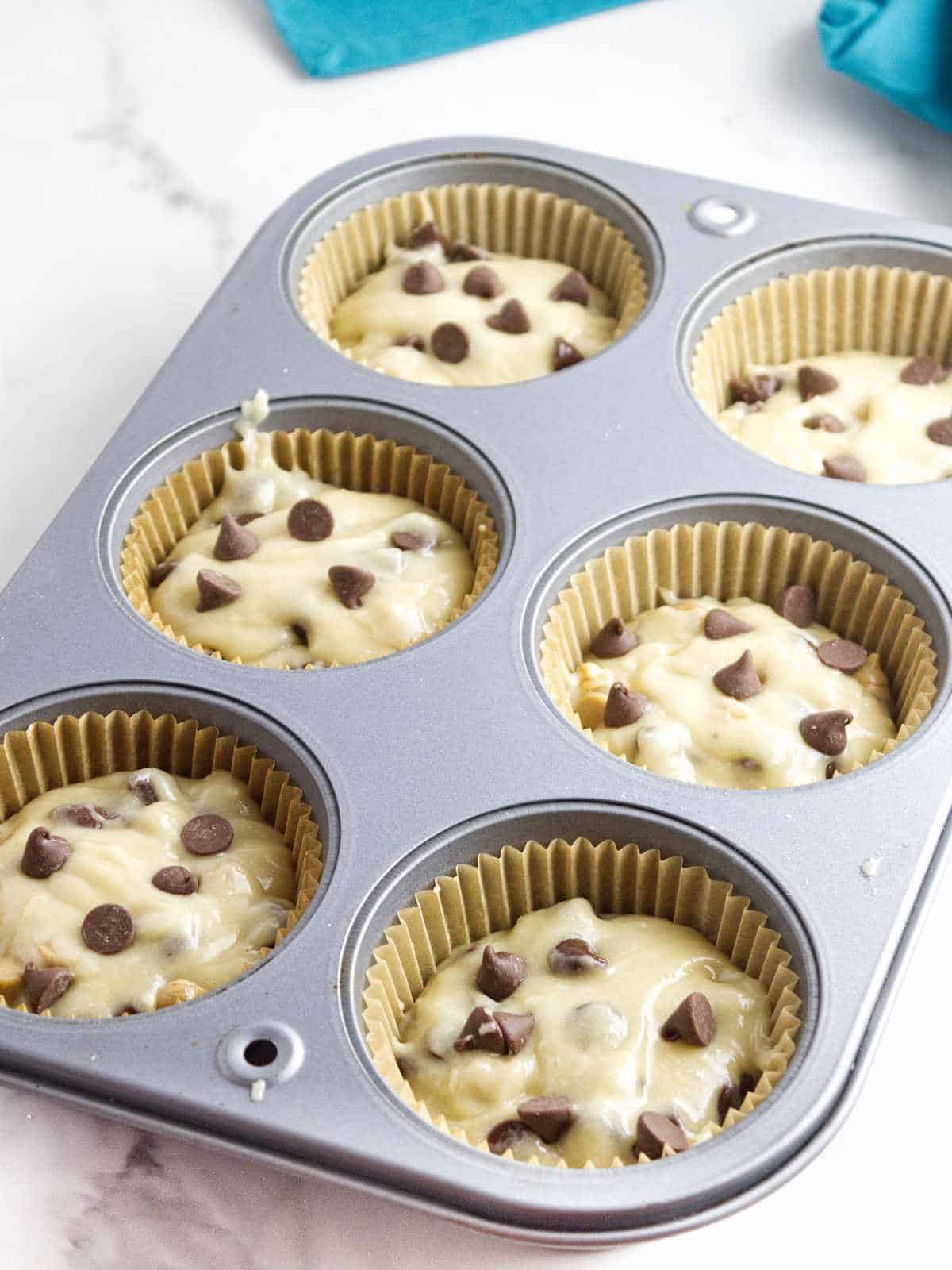 Jumbo muffin tins filled with chocolate chip muffin batter.