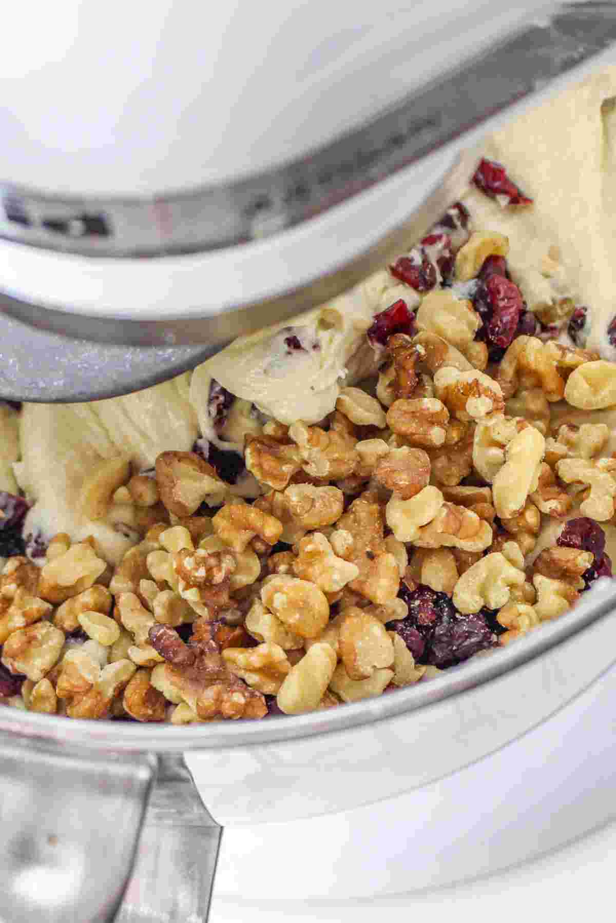 Mixing bread dough with raisins and nuts in a mixer.