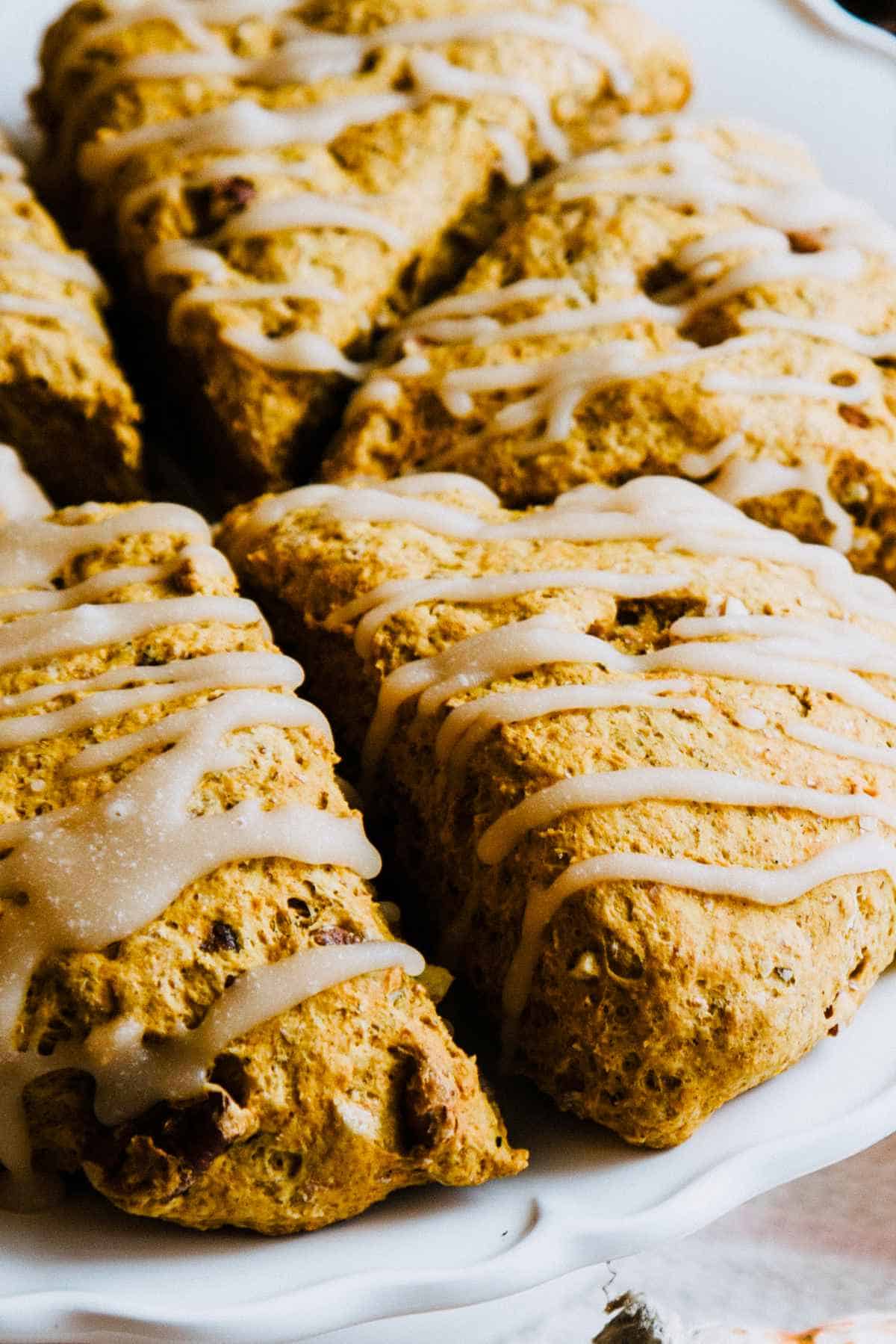 Pumpkin scones with maple icing on a platter.