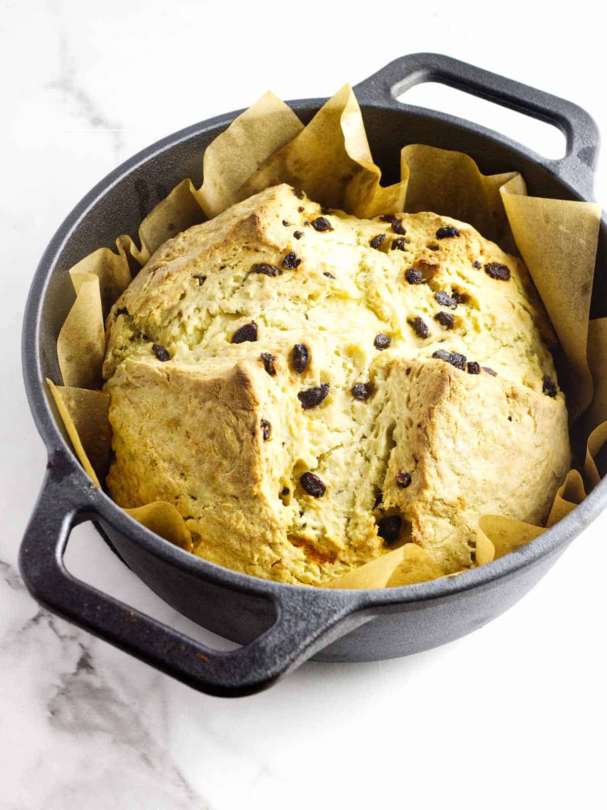 Soda bread with raisins in a cast iron Dutch oven, freshly baked.