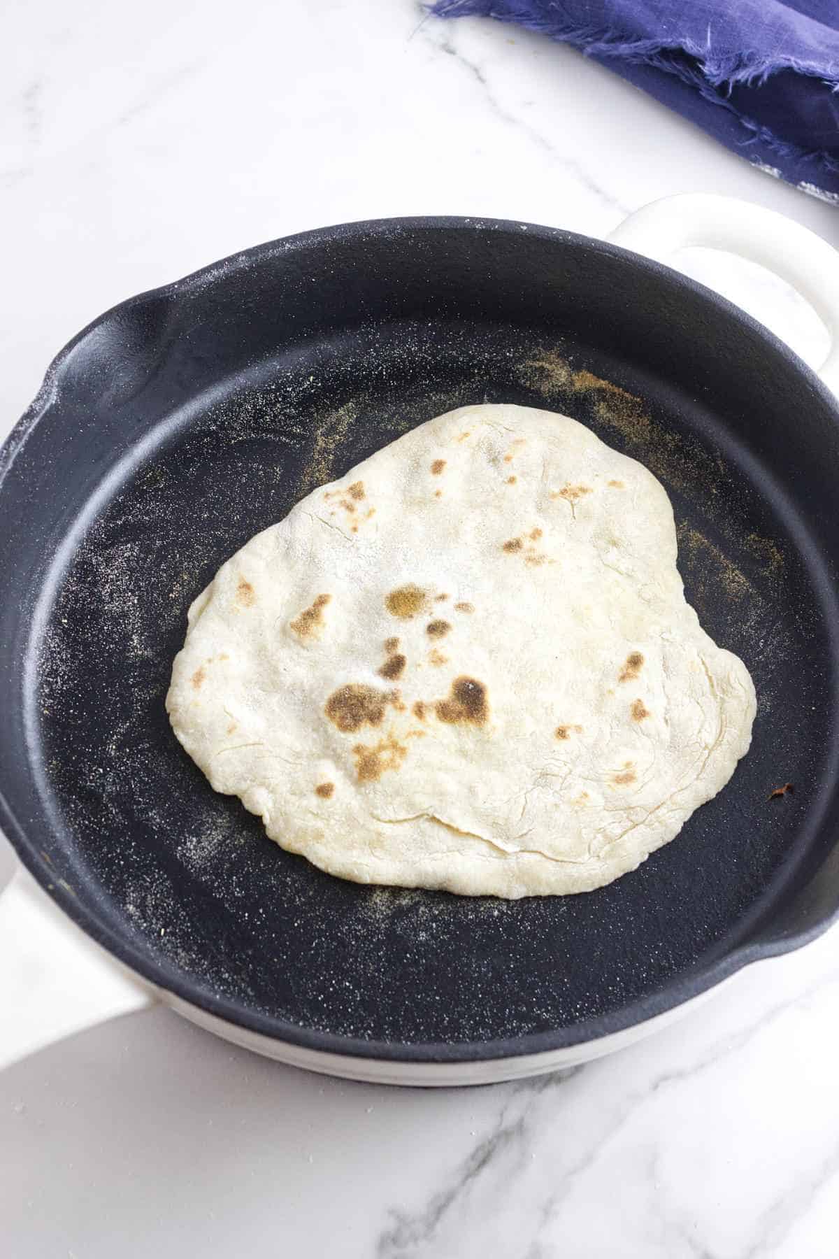 cooking naan in a hot cast iron skillet.