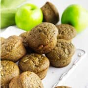 flaxmeal muffins on a serving plate with green apples nearby.
