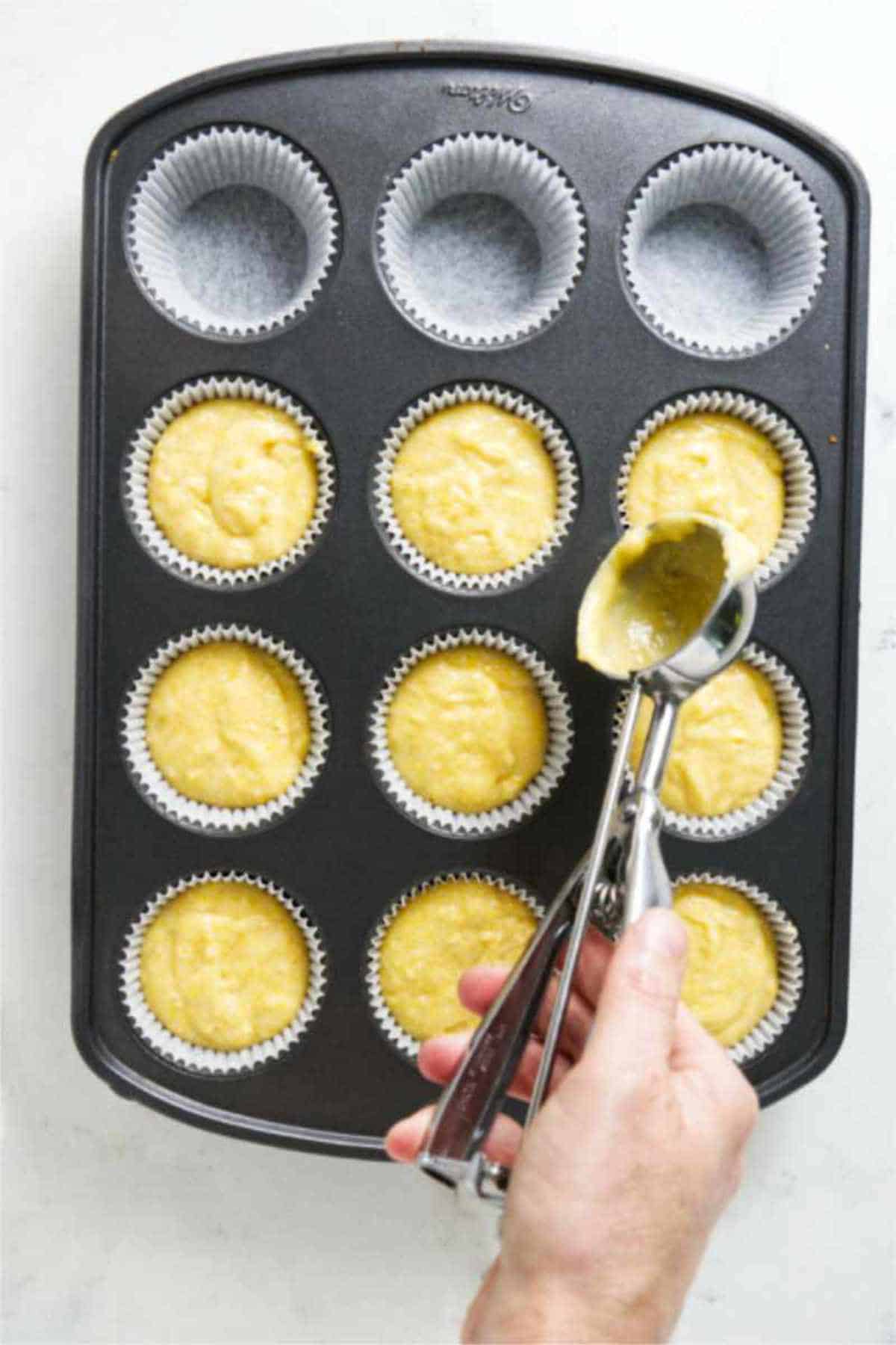 scooping batter into paper lined muffin tin.