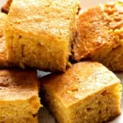 Honey butter cornbread slices stacked on a plate.