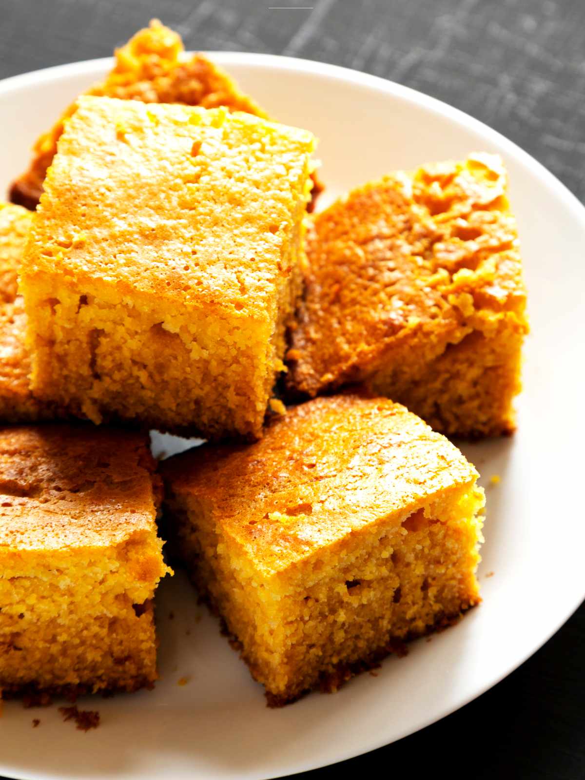Honey butter cornbread slices stacked on a plate.