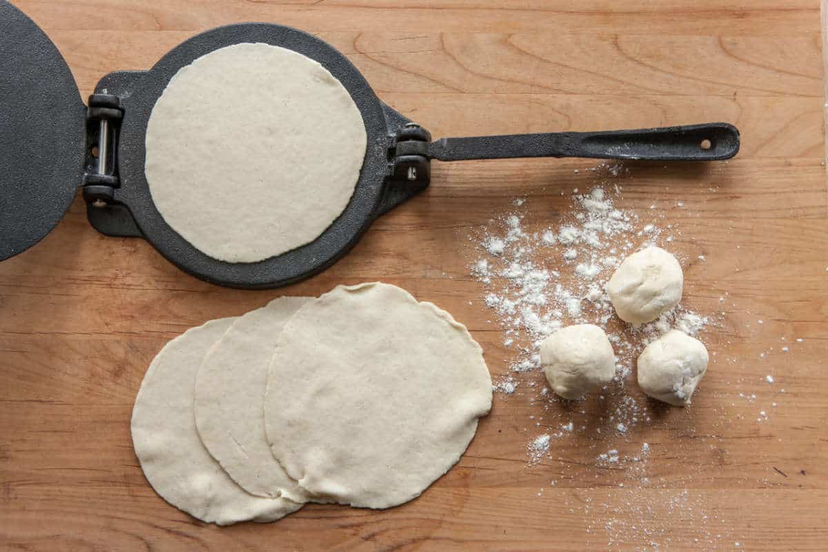 An overview of home made tortillas and a cast iron press.