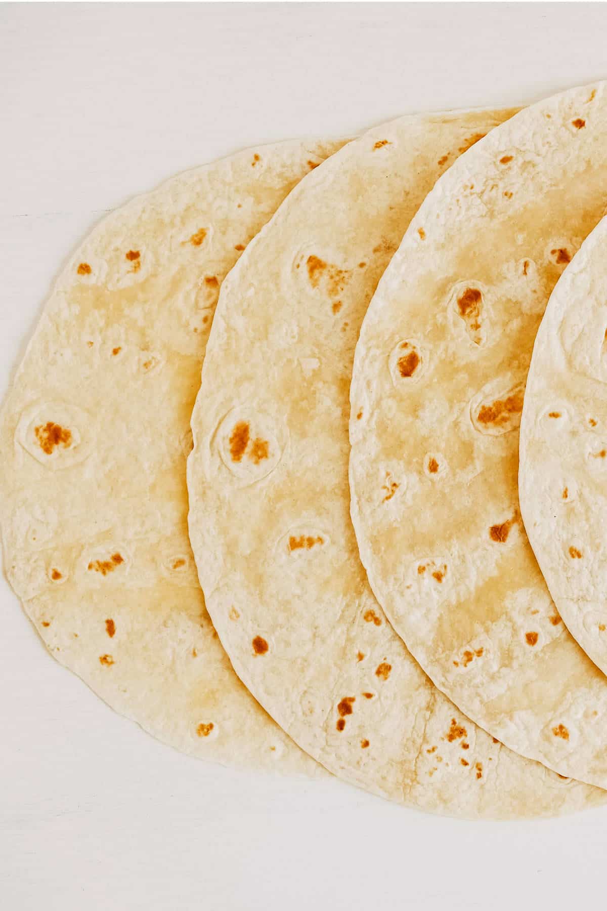 Thin flour tortilla on a white wooden table background.