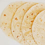 Thin pita bread on a white wooden table background.