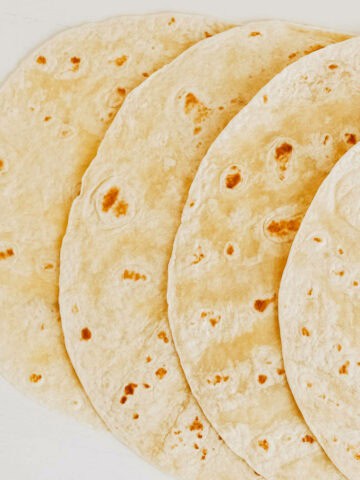 Thin pita bread on a white wooden table background.