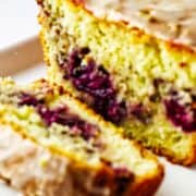 Lemon blackberry bread on a platter with glaze.