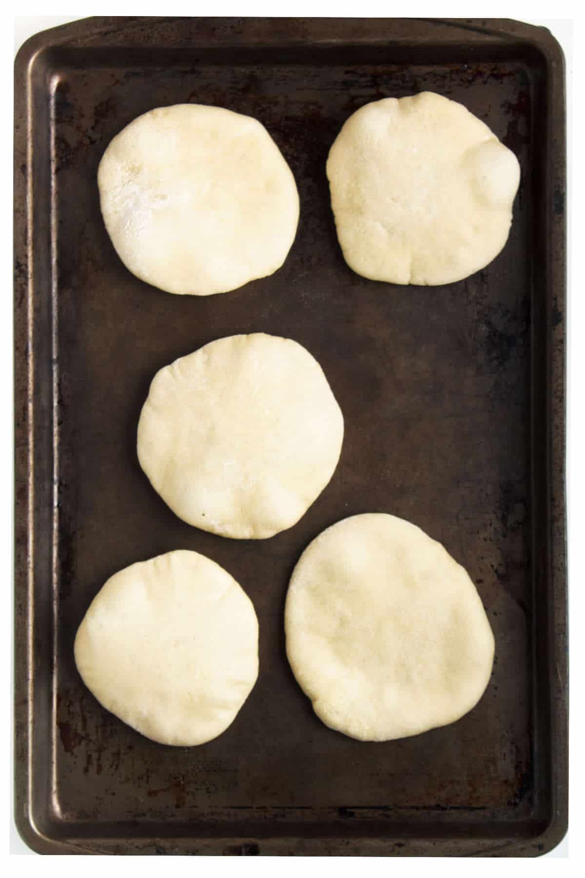 mini pita bread fresh baked on a baking sheet.