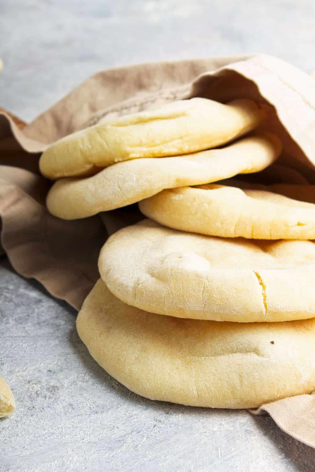 mini pita bread cooling on a wood cutting board.