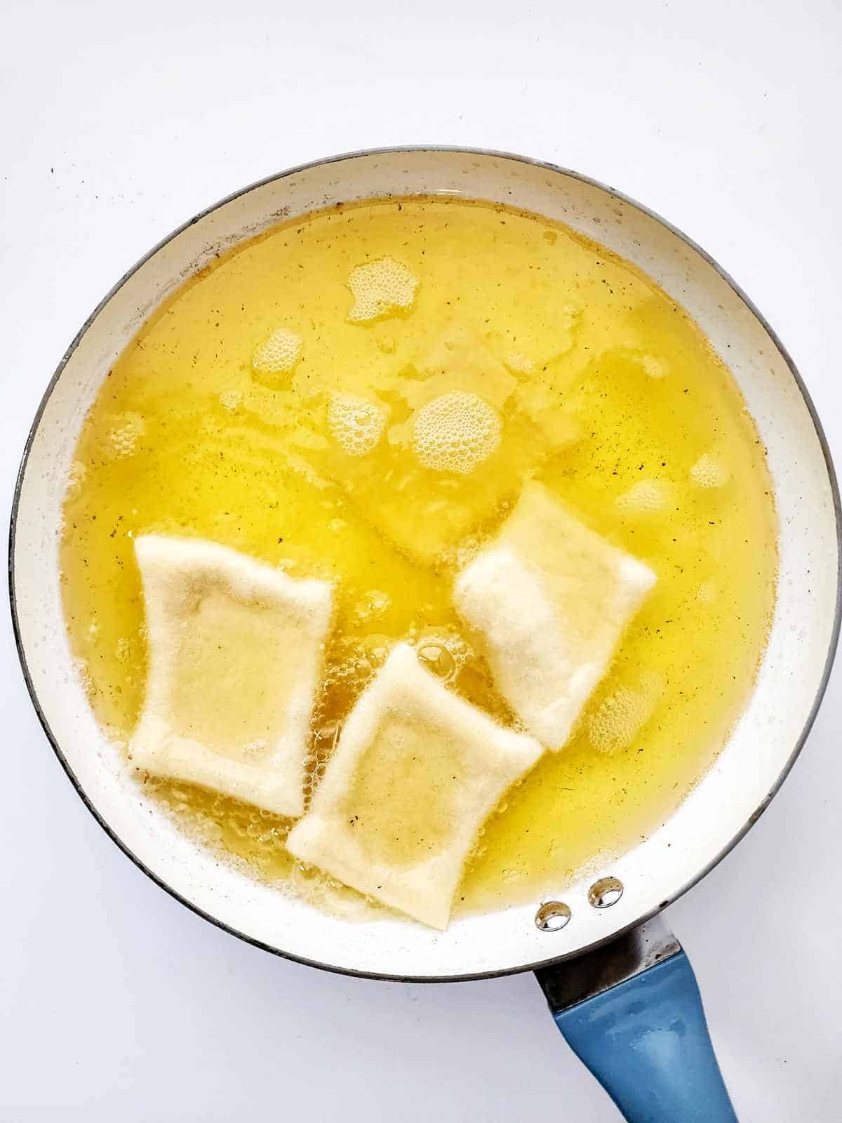 frying dough squares in hot oil in a skillet.