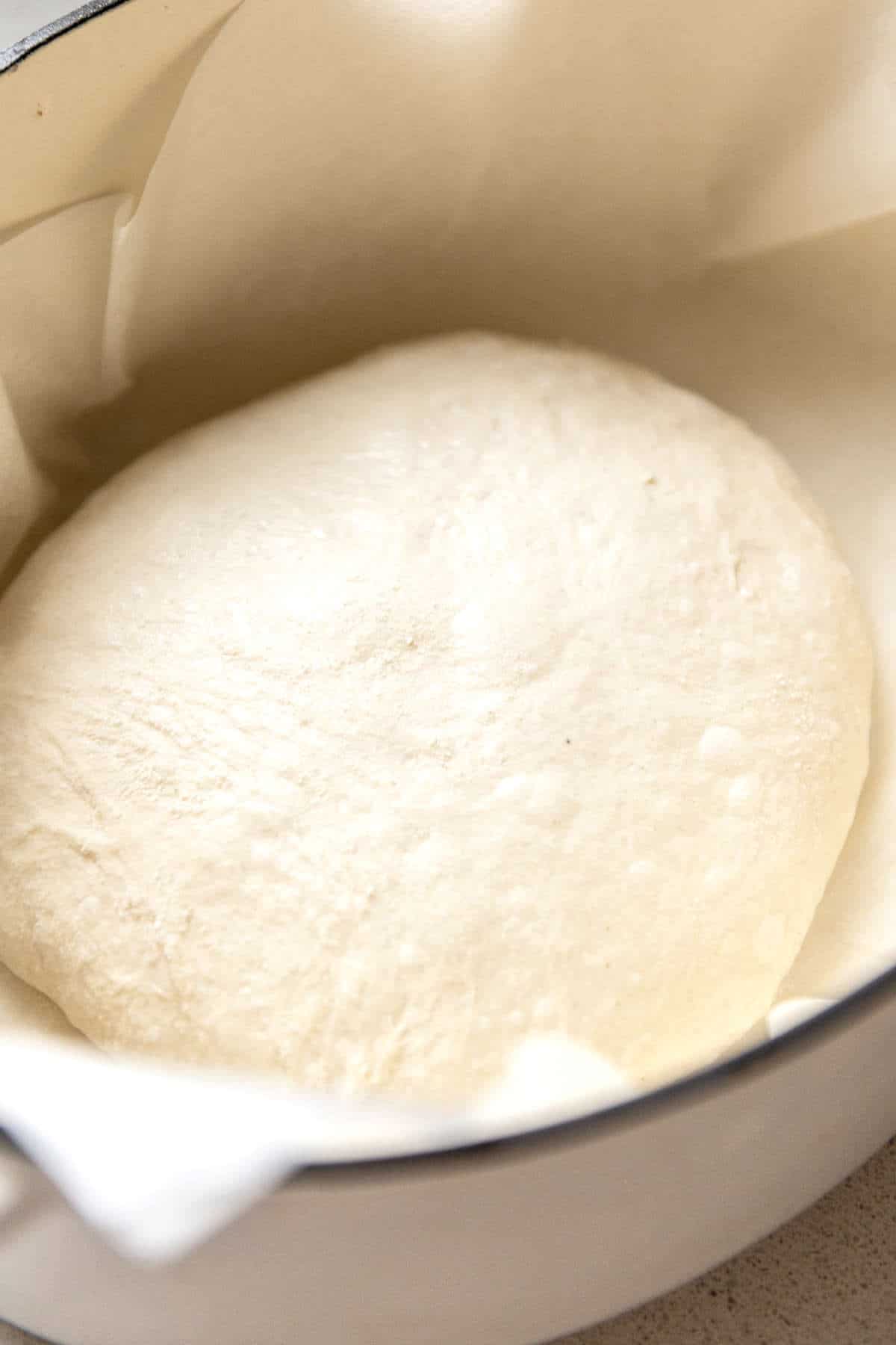 raw dough ready to be baked in a dutch oven with parchment paper.