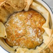 baked boule in a dutch oven with parchment paper.