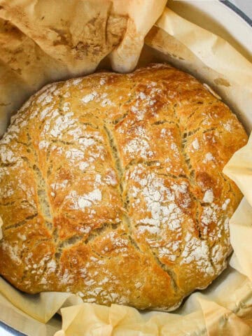 baked boule in a dutch oven with parchment paper.