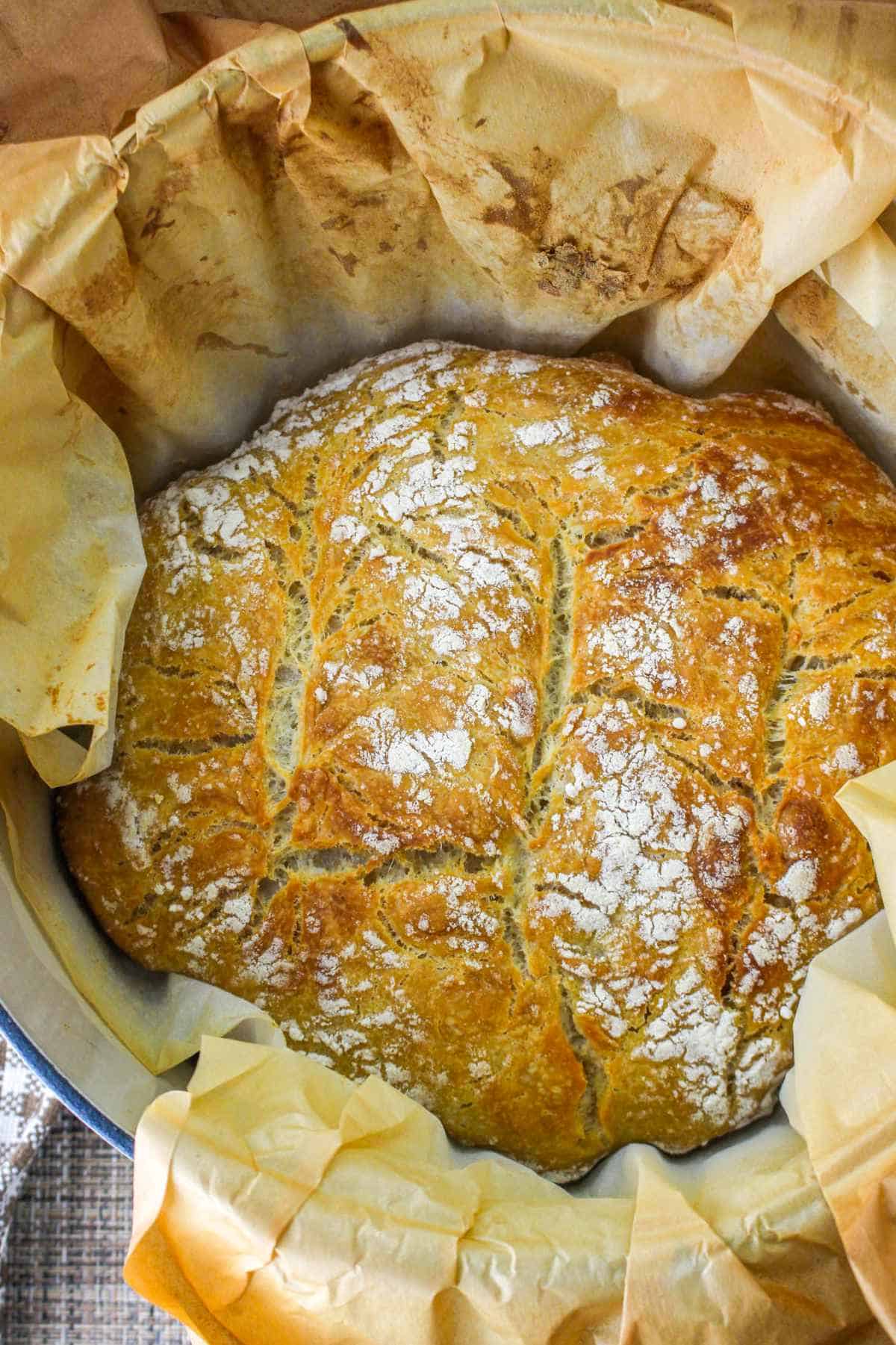 baked boule in a dutch oven with parchment paper.