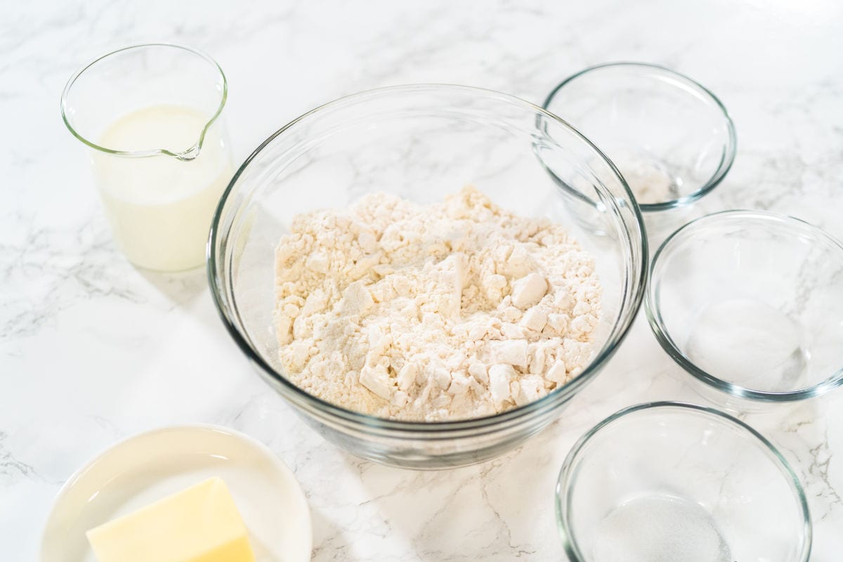 Measured ingredients in glass mixing bowls to fat tuesday donuts, paczki.