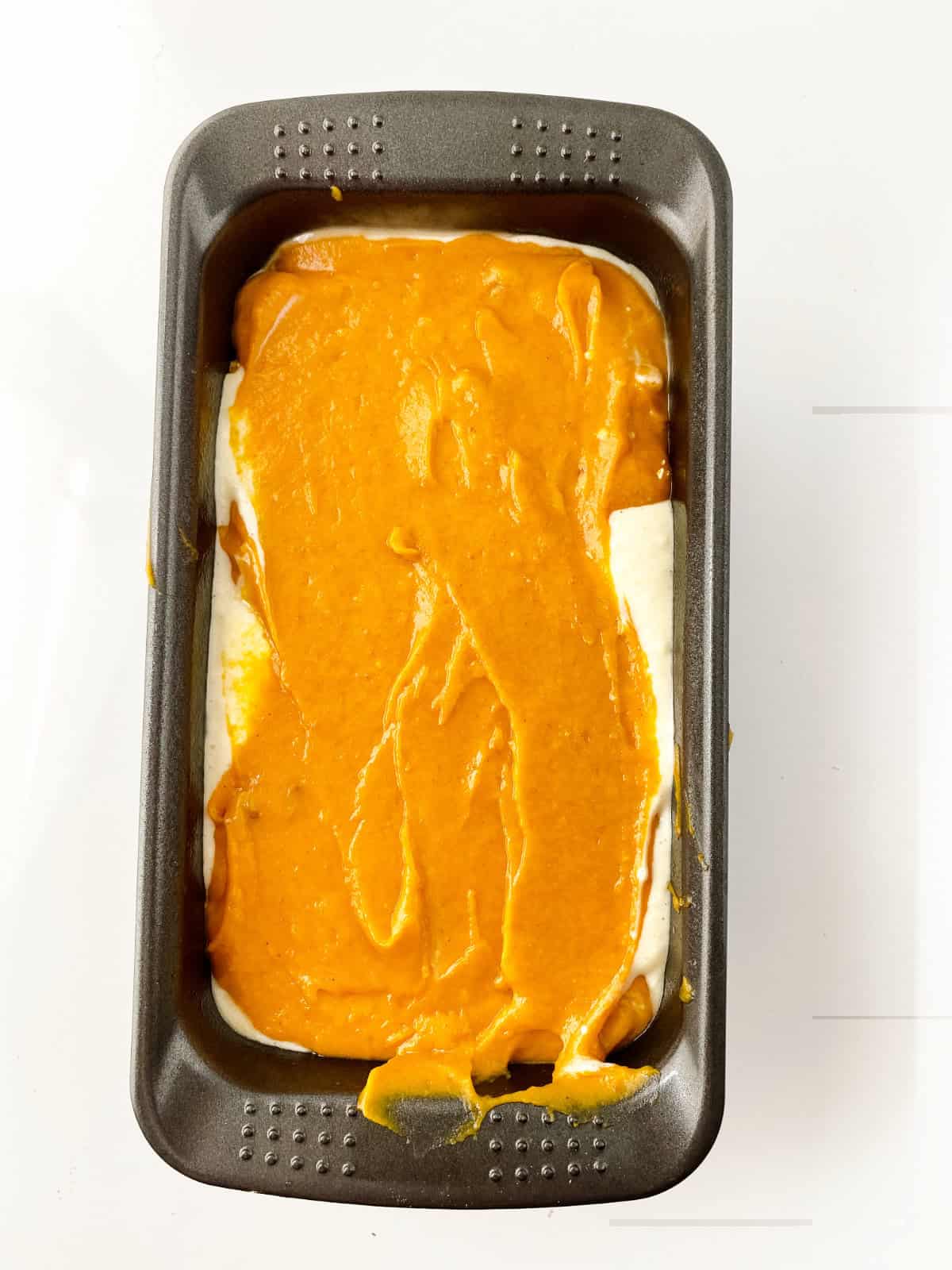 layering pumpkin batter and cream cheese batter in a loaf pan.