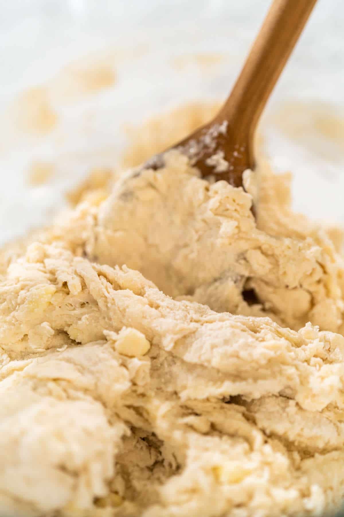 Mixing ingredients in a large glass mixing bowl to make sourdough discard cinnamon rolls.