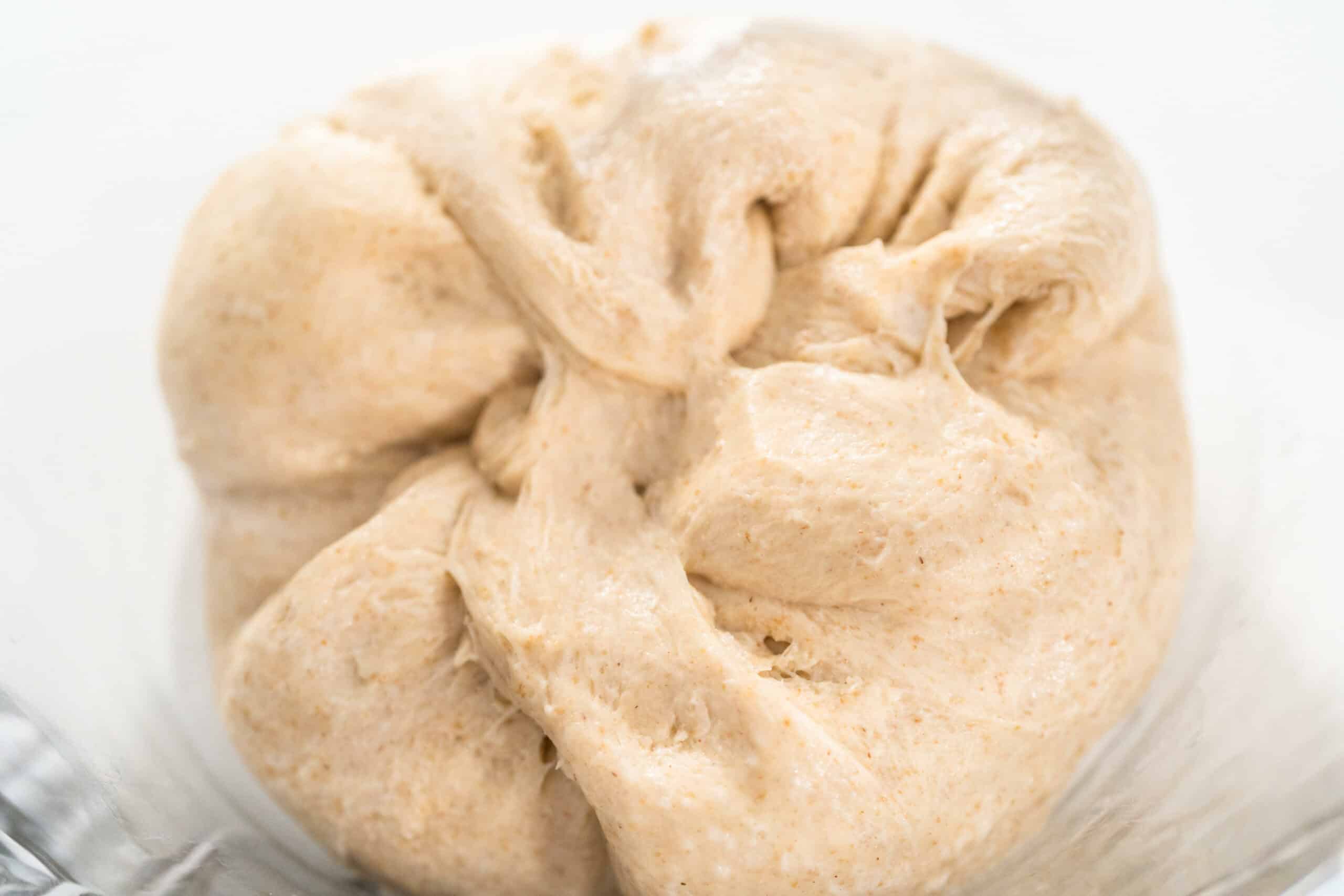 stitching dough in a glass mixing bowl to bake the cinnamon rolls.