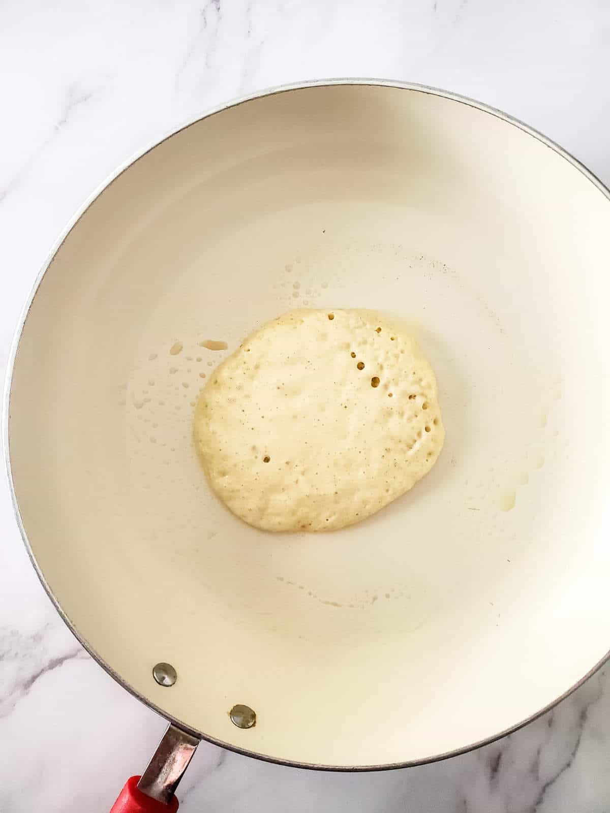 cooking sourdough discard pancake batter in a skillet for 4 inch pancakes.