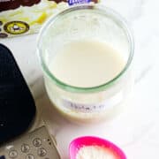 A jar labeled "Potato" contains a cloudy liquid, beside a pink spoon with white powder—possibly for a potato flake sourdough bread starter—a digital scale, and a box of instant mashed potatoes on a white surface.