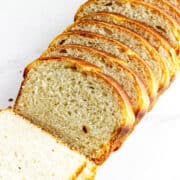 A loaf of potato flake sourdough bread, partially sliced, with several even slices fanned out on a white surface. The bread features a golden-brown crust and a soft, airy interior.