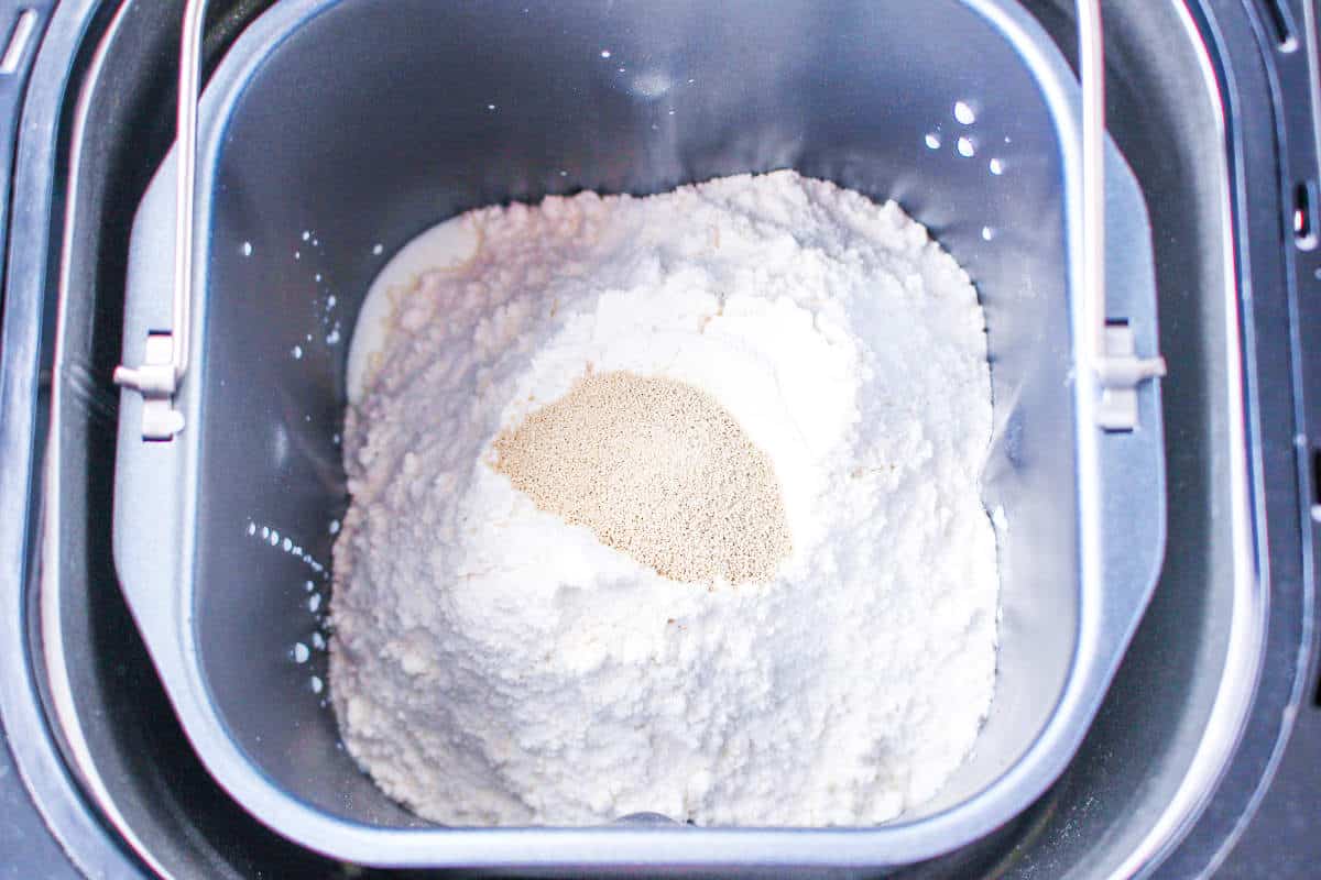 A close-up of a bread machine pan filled with flour, yeast, and other dry ingredients, ready to be mixed for homemade bread machine buttermilk bread.
