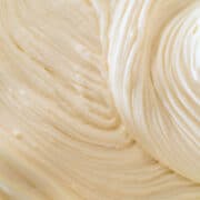 Close-up of smooth, creamy, light-colored cream cheese frosting with visible swirls and textured ridges created by spreading.