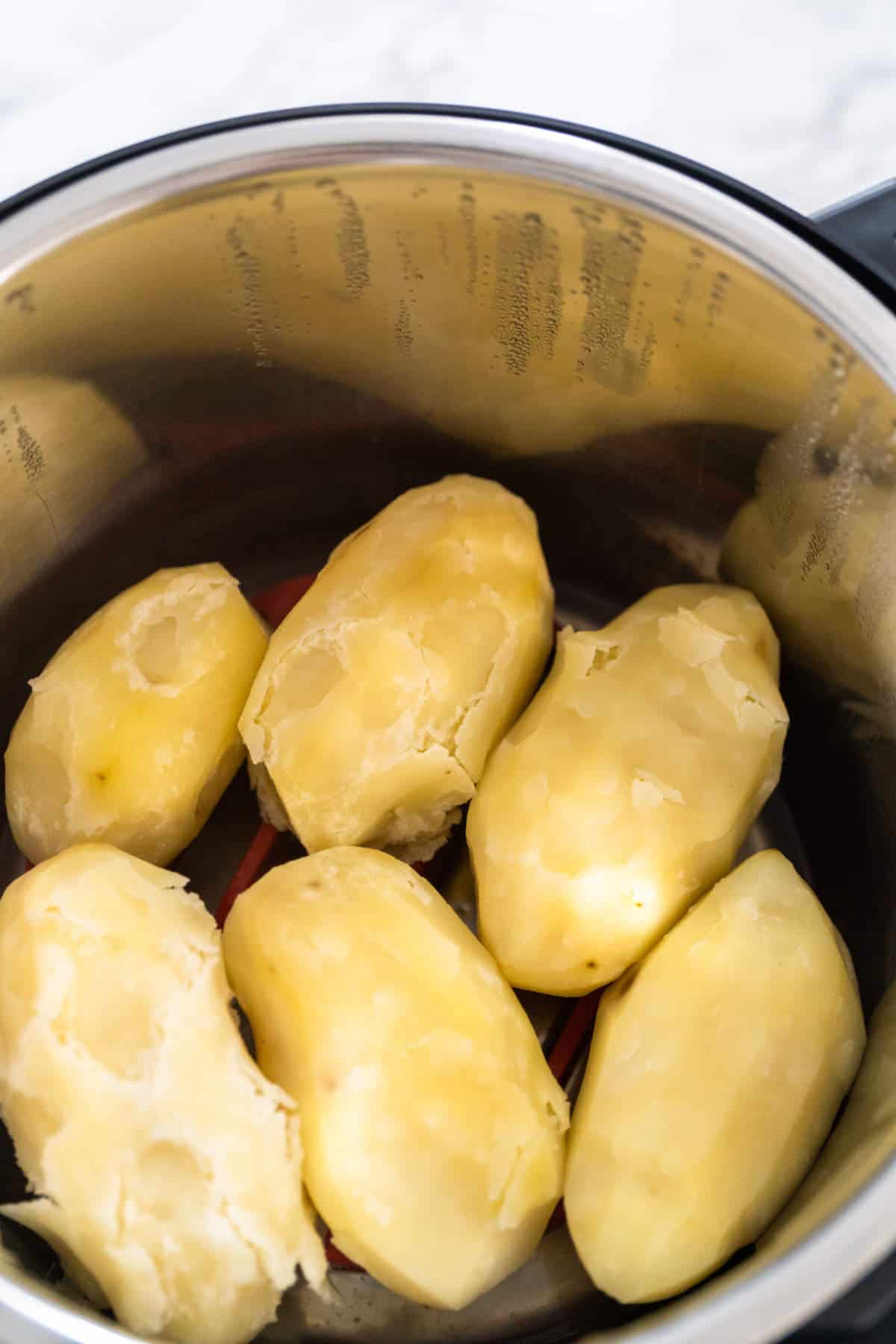 Several peeled, boiled potatoes are placed inside a stainless steel pot, ready to be transformed into traditional Irish farls or classic Irish potato pancakes.