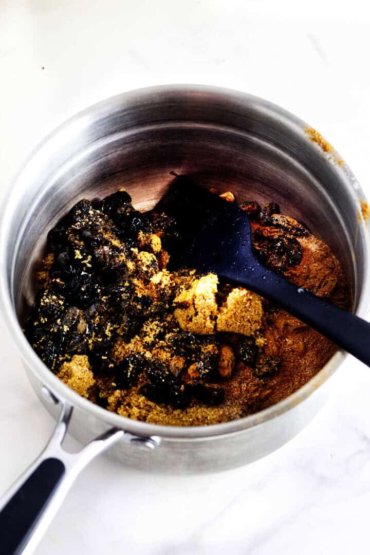 Raisins, sugars, spices, molasses, and water combined in a saucepan for Sailor Jack muffins.