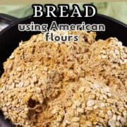 A round loaf of Irish wheaten bread topped with oats sits in a black cast iron pan. Text over the image reads: "Irish Wheaten Bread using American flours.